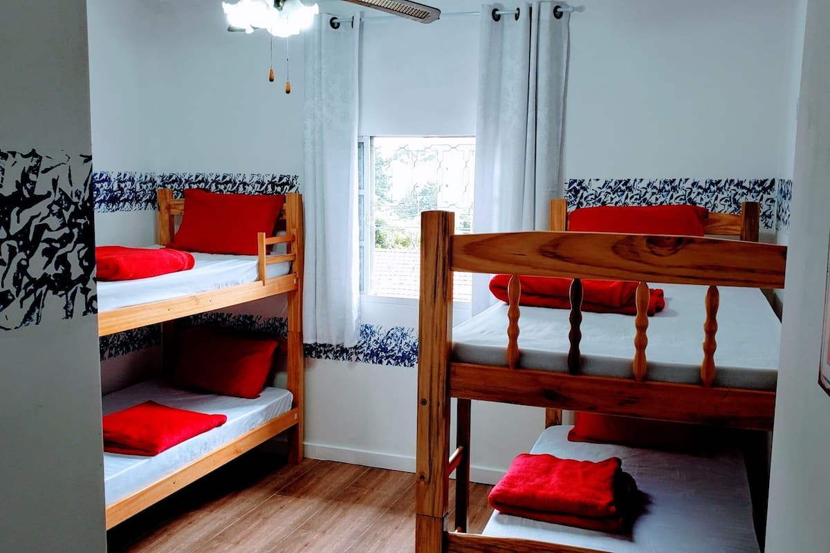 A room with two bunk beds, each with red pillows and a wooden headboard.