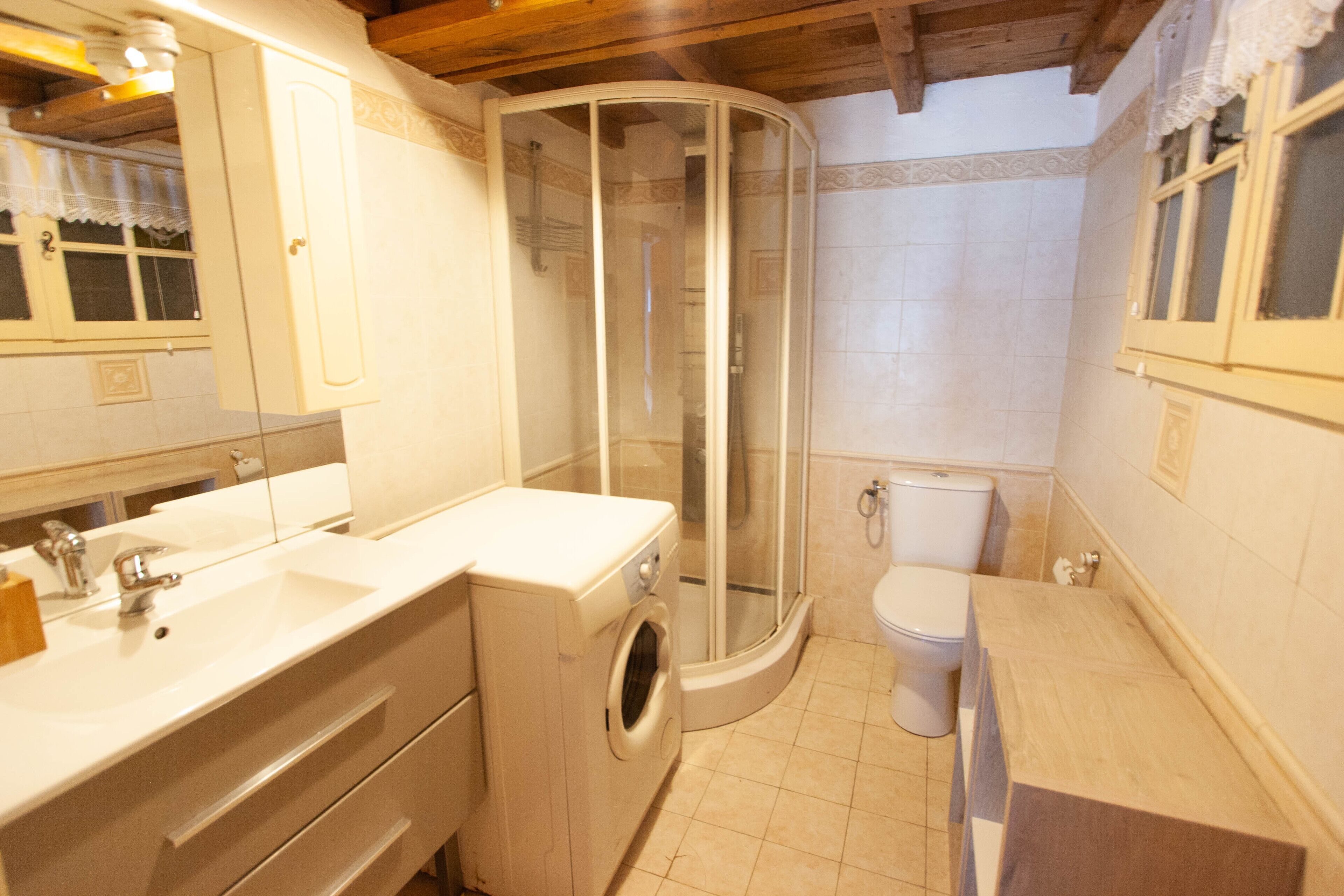 Un bagno compatto con lavatrice integrata, cabina doccia in vetro e water.