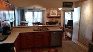 A kitchen with wooden cabinets, a dishwasher, and a stone accent wall. - Peaches and Beaches.... come eat some fresh peaches, close to the island beaches (Saint Marys)