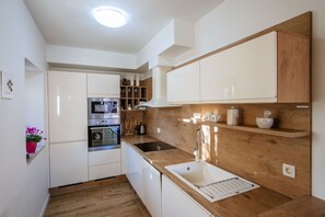 Een moderne keuken met witte kastjes, een houten aanrecht en een roestvrijstalen oven.