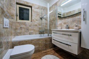 Een moderne badkamer met een bad, toilet en wastafel.