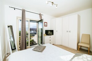 A bedroom with a bed, a TV, a wardrobe, a chair, and a balcony with a view. - Villa Castelo Coza ZadarVillas (Vinjerac)