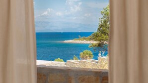 A coastal view through a window with stone walls and a clear blue sea. - Apartments Habek (Jelsa)