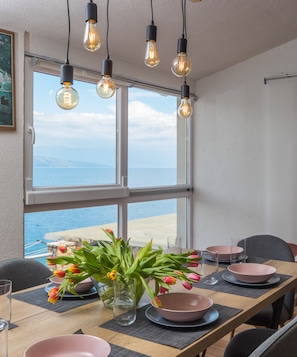 A dining table with pink bowls and tulips, overlooking a beach. - Apartments Habek (Jelsa)
