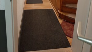 Un pasillo con una escalera de madera, escalones alfombrados y una puerta al final.
