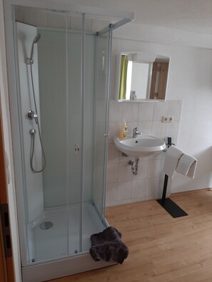 Une salle de bain moderne avec une douche à parois de verre, un lavabo et un miroir au-dessus.