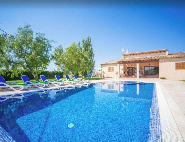Relax by the pool surrounded by comfortable lounge chairs and lush greenery.