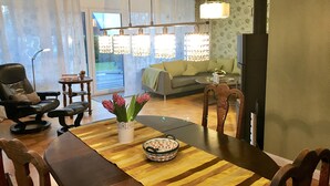A living room with a sofa, a dining table with chairs, a coffee table, and a vase with flowers. - Inselferien Micheel (Fehmarn)