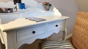 A white desk with two drawers, a small vase with flowers, and a magazine on the desk. - Inselferien Micheel (Fehmarn)
