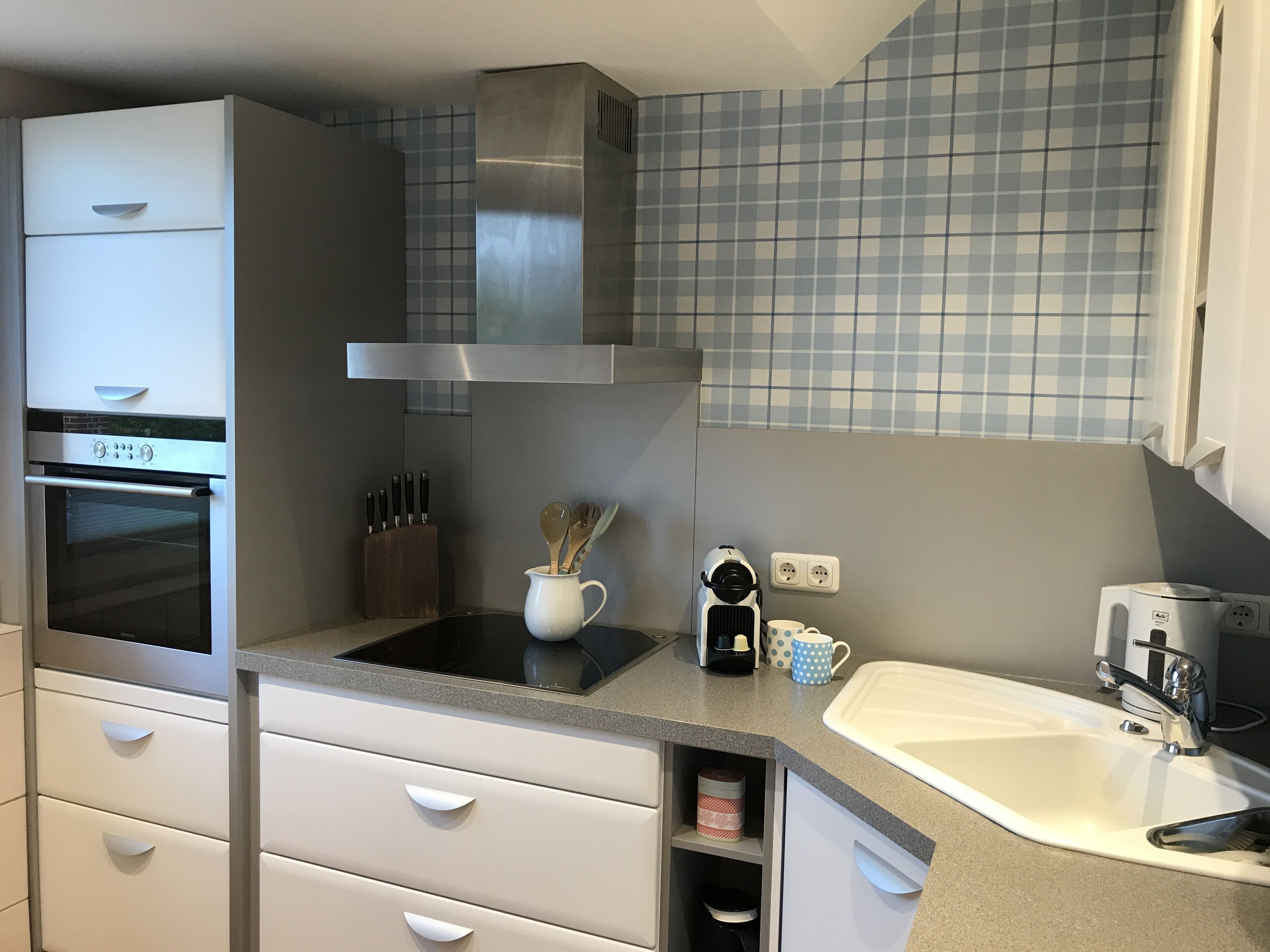 A compact kitchen with a built-in oven, a coffee maker, and a sink.