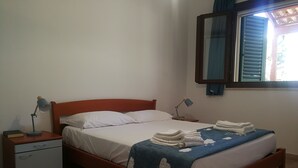 A neatly made bed with a blue blanket, a bedside lamp, and a small bedside table with a book and a lamp. - Villa Serena - Torre Inserraglio Nardò (Nardò)