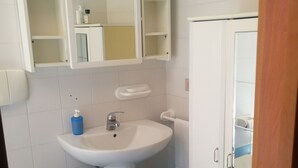 A bathroom with a white sink, blue-tiled walls, a white toilet, and a cabinet with a mirror. - Villa Serena - Torre Inserraglio Nardò (Nardò)