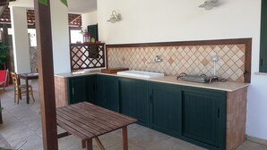 A kitchen with green cabinets, a wooden table, and a tiled backsplash. - Villa Serena - Torre Inserraglio Nardò (Nardò)
