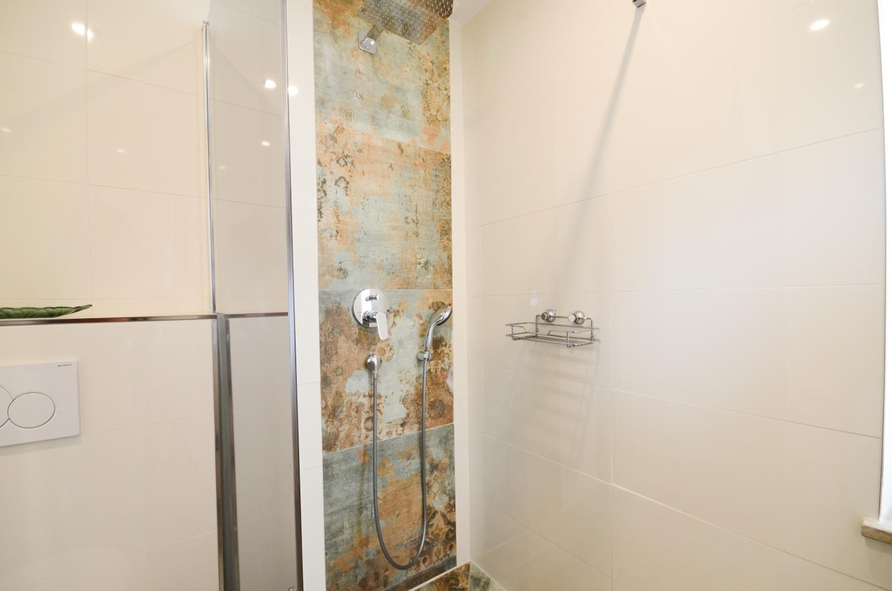 A shower with a glass door, a wall-mounted towel rack, and a control panel.