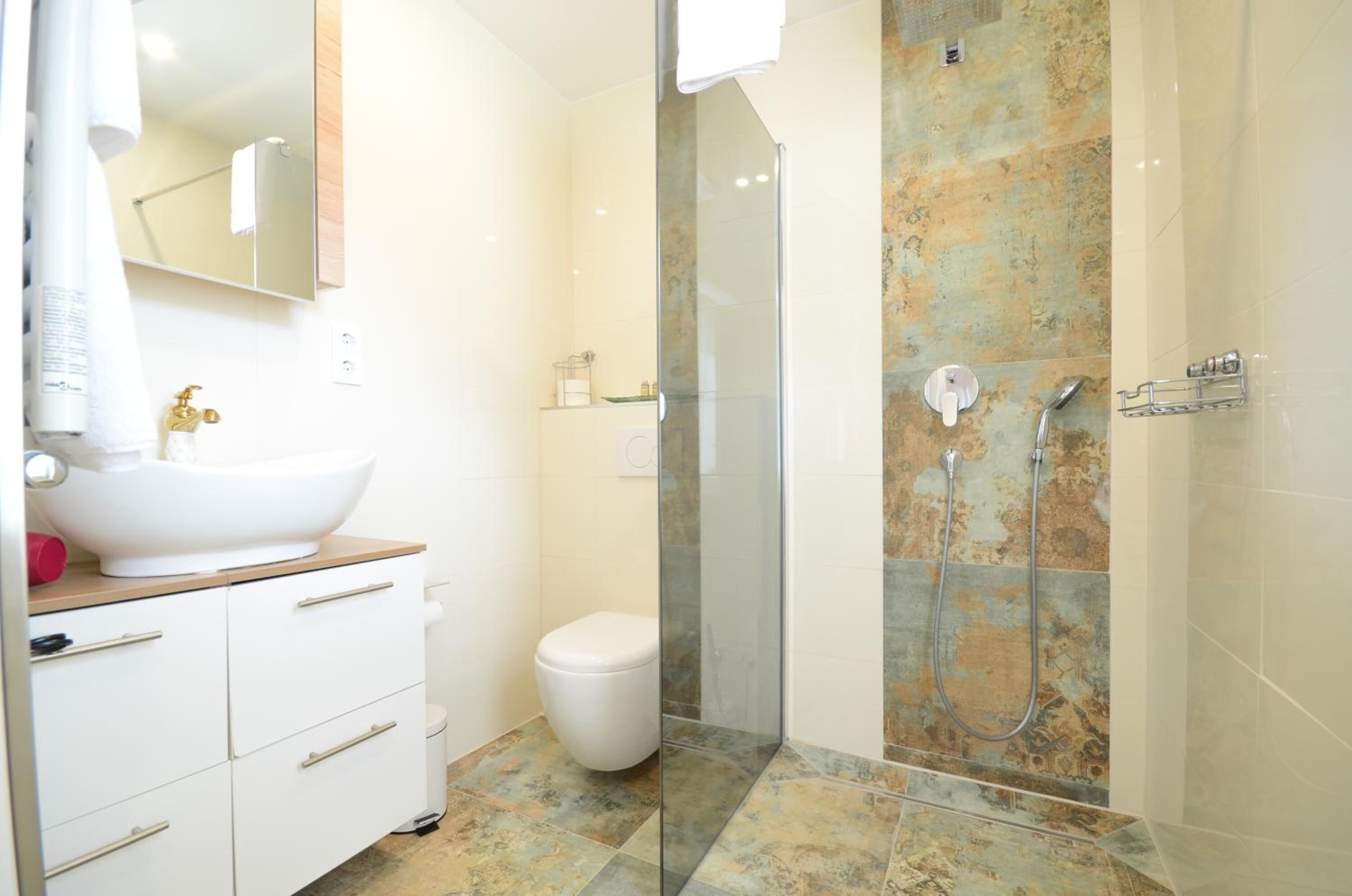 A modern bathroom with a white sink, a toilet, and a glass-enclosed shower area.