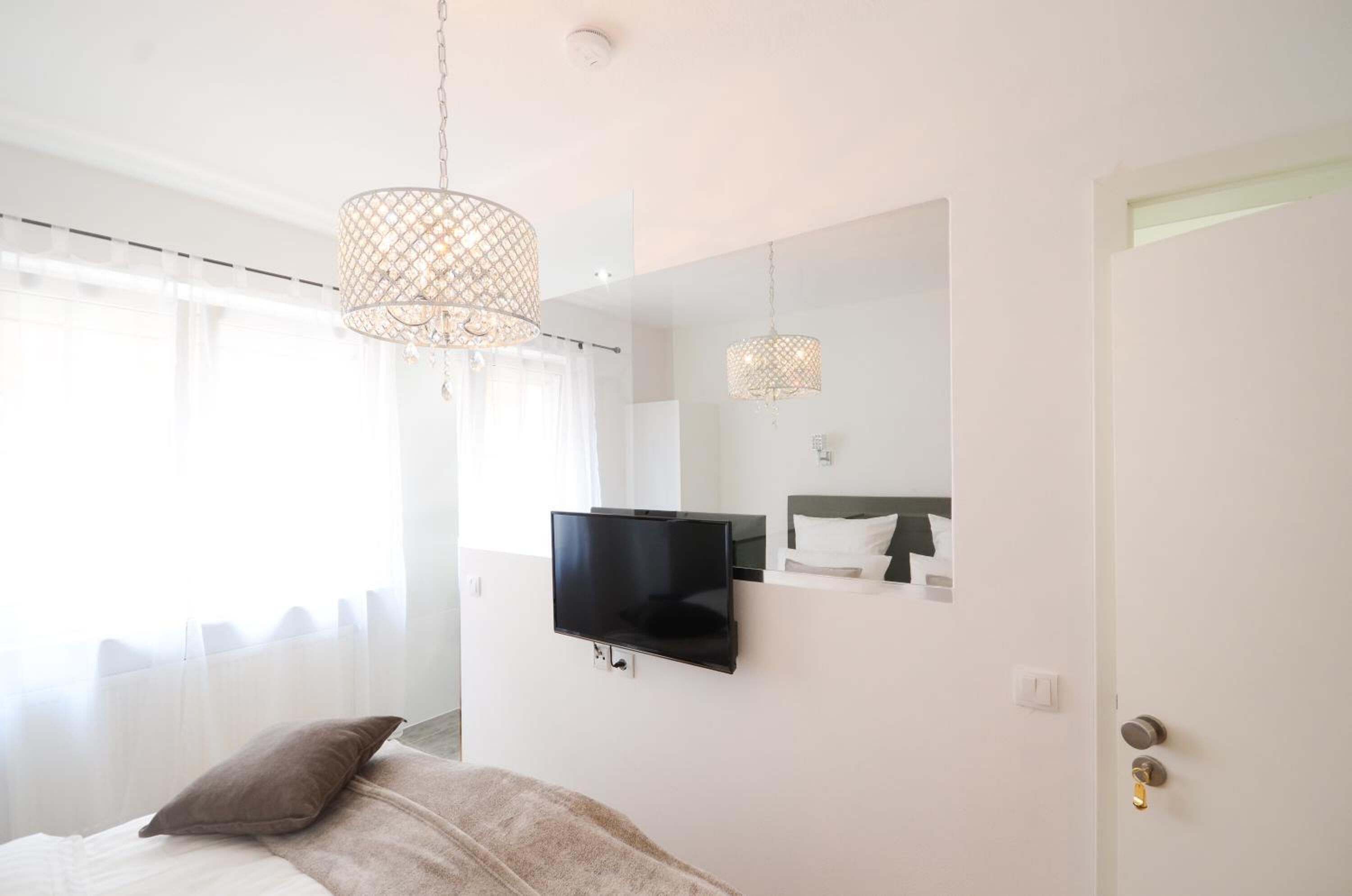 Une chambre moderne équipée d’un lit, d’un téléviseur à écran plat et de deux lampes suspendues.