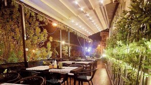 Um restaurante interno com piso de madeira, mesas e cadeiras.