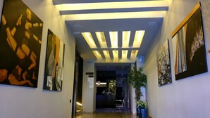 Uma área de recepção moderna com design no teto, balcão de atendimento e obras de arte nas paredes.