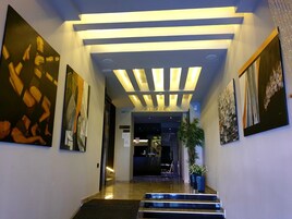Un área de recepción moderna con diseño en el techo, un mostrador de recepción y obras de arte en las paredes.