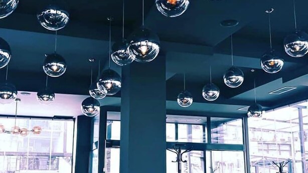 Interior de restaurante moderno com luminárias pendentes esféricas, grandes janelas e design contemporâneo e elegante.