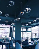 Un interior de restaurante moderno con lámparas colgantes esféricas, ventanas amplias y un diseño limpio y contemporáneo.