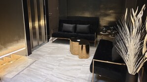 Um interior moderno com um sofá escuro, uma mesa de centro redonda e um vaso decorativo.