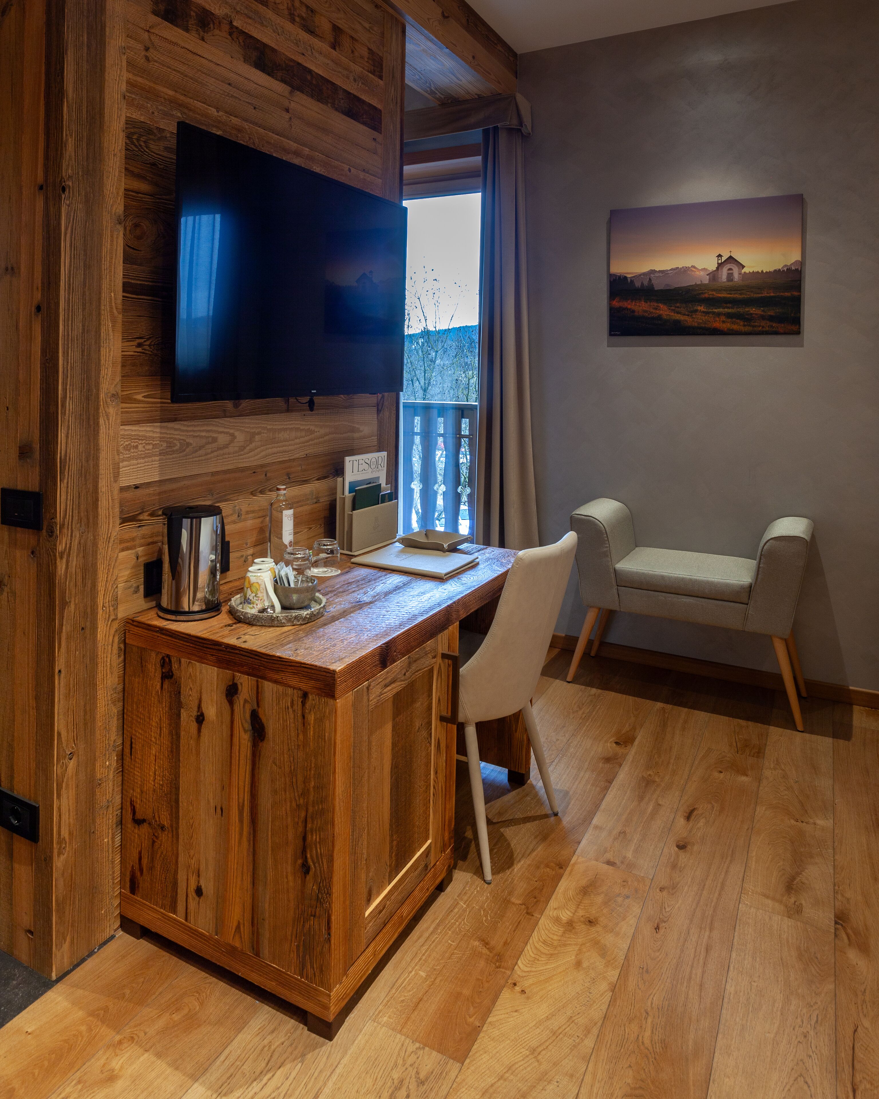 Un área de bar con barra de madera, un televisor de pantalla plana, una cafetera y una pequeña mesa con una silla.