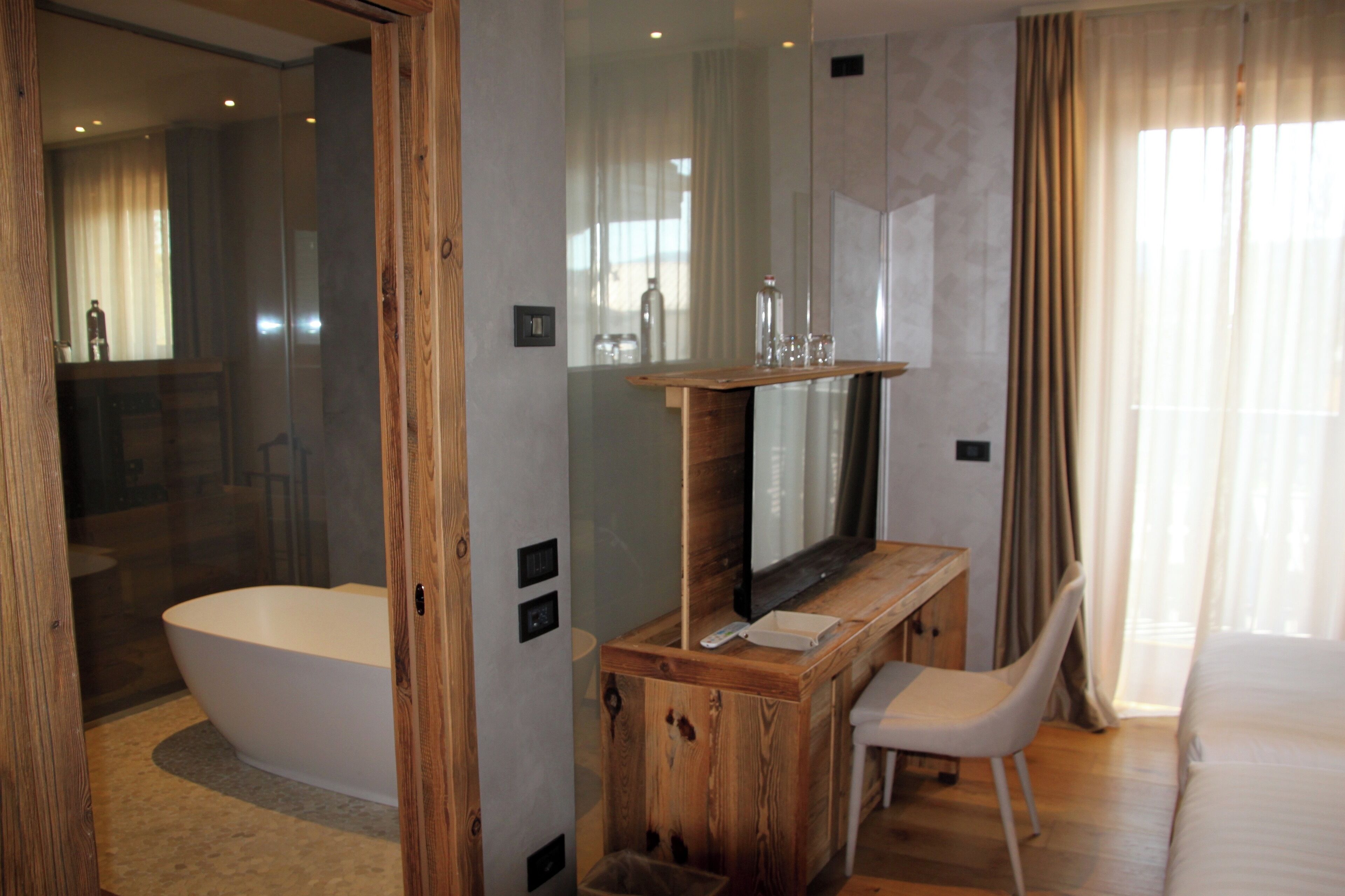A modern bathroom with a freestanding bathtub, a wooden vanity with a mirror, and a white chair.