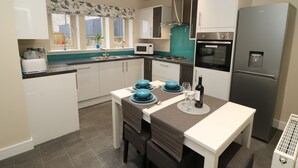 A modern kitchen with white cabinets, a stainless steel refrigerator, a built-in oven, and a gas stove.