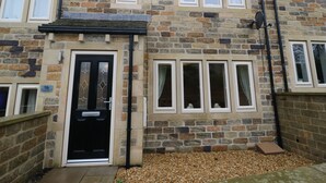 A stone building with a black front door, multiple windows, and a small porch area.