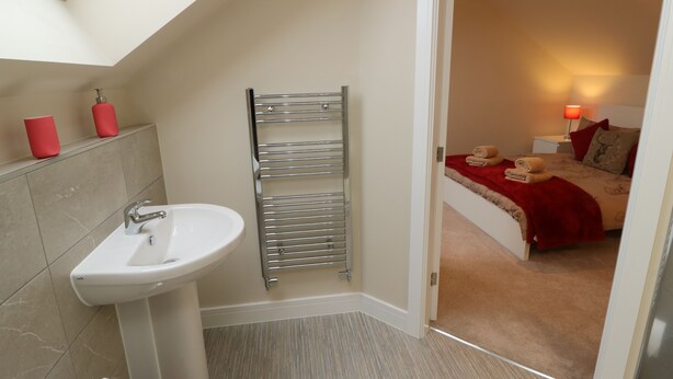 A modern bathroom with a skylight, a sink, and a towel rack.