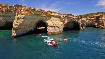 Una zona costera con una gran formación rocosa que presenta dos arcos naturales sobre aguas azul cristalino.