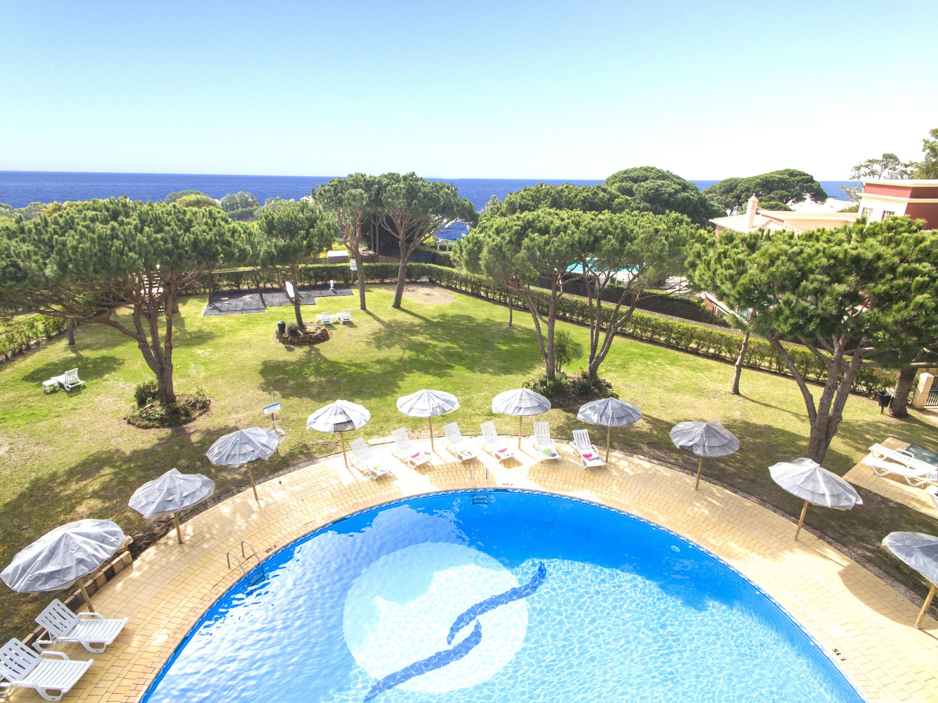 Una piscina con vistas al mar, rodeada de sillas de descanso y sombrillas.