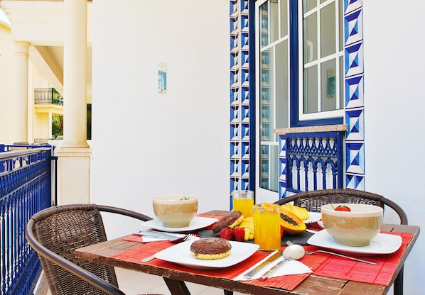 Una mesa dispuesta con cosas para el desayuno, incluyendo un cuenco, un plato con un pastel y un vaso de jugo de naranja.