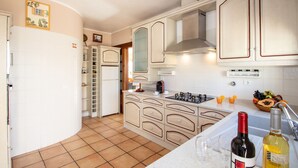 A kitchen with white cabinets, a stove, and a sink. There are two bottles on the counter. - Villa Dominica (Lagoa)