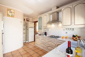 A kitchen with white cabinets, a stove, and a sink. There are two bottles on the counter.