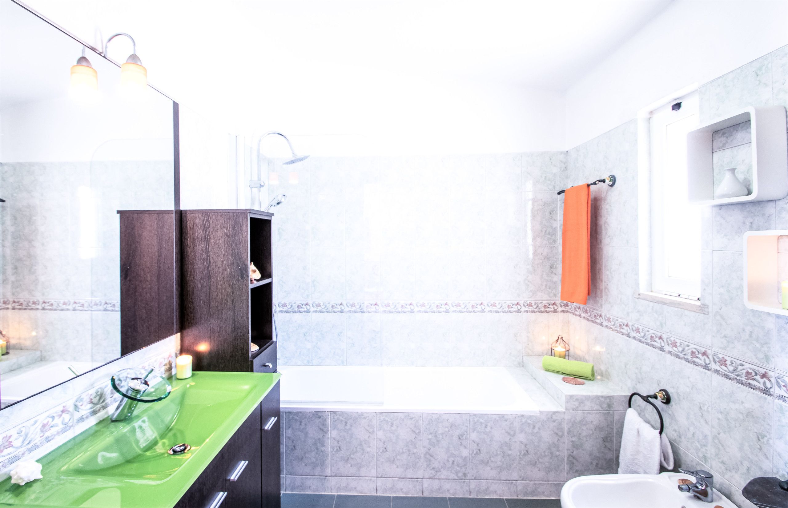 A modern bathroom with a green vanity, a large mirror, a bathtub, and a shower.