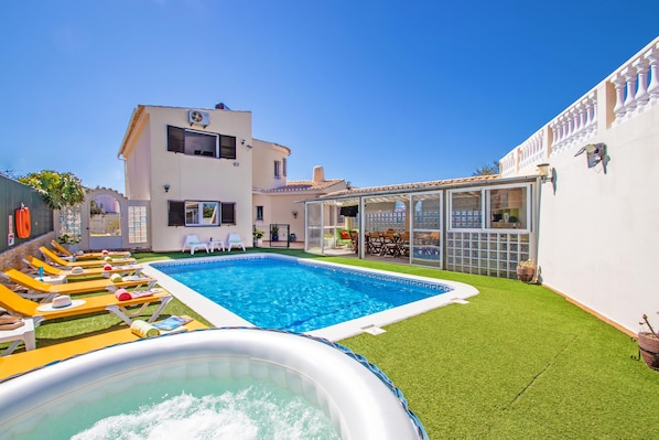 A swimming pool with lounge chairs, a hot tub, and a building with a balcony. - Villa Dominica (Lagoa)