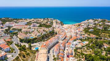 Vista aérea de un pueblo costero con playa, edificios residenciales y un cielo azul despejado.