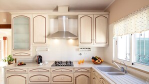 A kitchen with a central island, double sink, and a window with a decorative valance. - Villa Dominica (Lagoa)