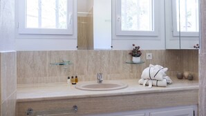 A bathroom with a beige marble countertop, a sink, a mirror, and a towel rack with towels. - VILLA IRIS-Feet in the water, Isolella peninsula, 5 bedrooms, swimming pool, sea view (PIETROSELLA)