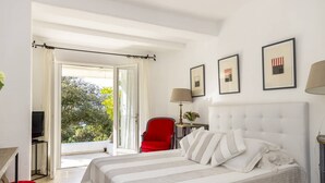 A hotel room with a large bed, a red chair, a TV, and a view of the outdoors. - VILLA IRIS-Feet in the water, Isolella peninsula, 5 bedrooms, swimming pool, sea view (PIETROSELLA)