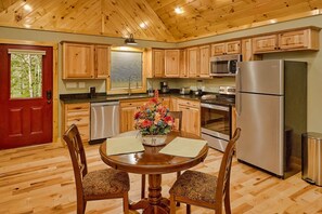 A wooden-paneled kitchen with a dining table, chairs, and a refrigerator.