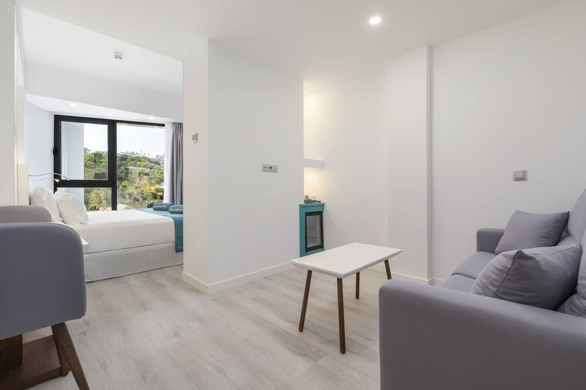Una sala de estar moderna con un sofá, una mesita y una cama con vistas a zonas verdes.