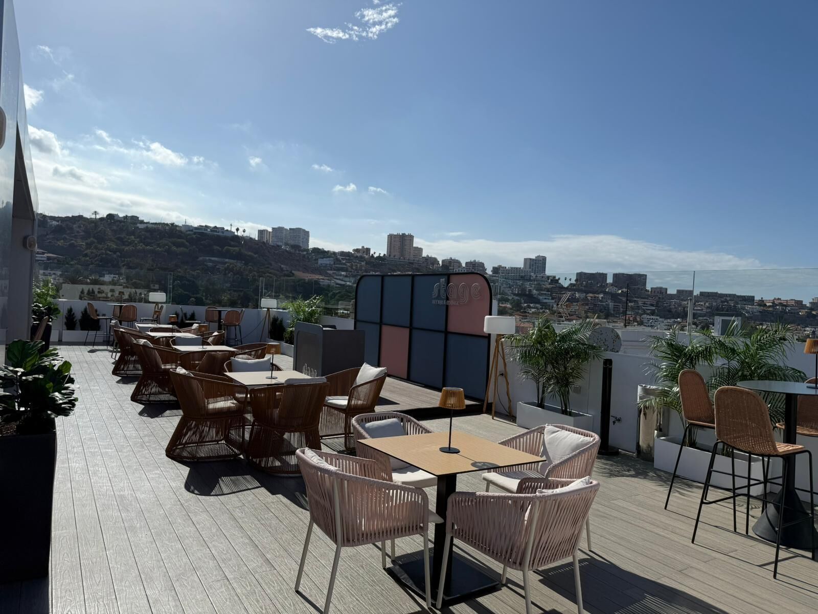 Een terras buiten met rieten meubilair en uitzicht op de stad.