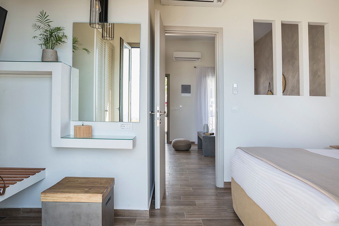 Um quarto moderno com uma cama, uma mesa de cabeceira, um espelho e uma planta em vaso.