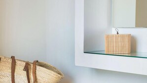 A room with a concrete bench, a woven basket, and a small wooden box on a glass shelf. - Diana Suites (Kefalonia)