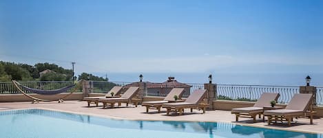 Piscine extérieure en saison, parasols, chaises longues