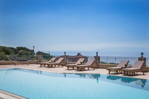A pool area with lounge chairs and a hammock. - Diana Suites (Kefalonia)