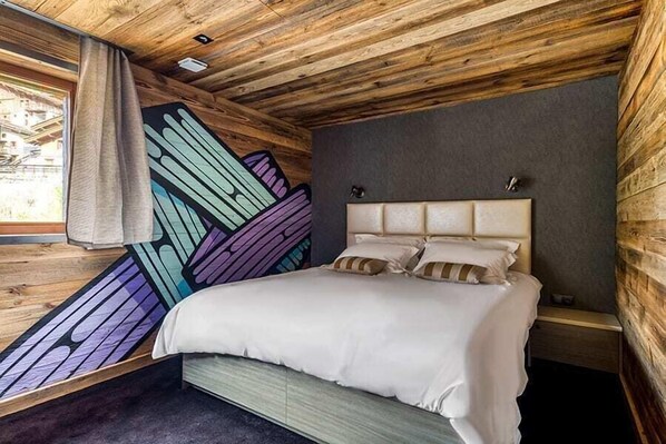 Un dormitorio con una cama, una mesita de noche y una pared con diseño geométrico.